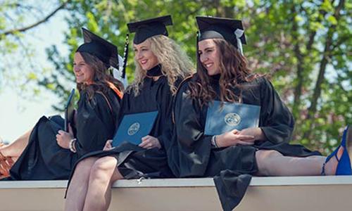 Three female students taking pictures after commencement